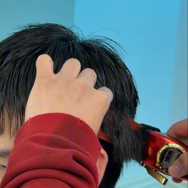 Finn clipper-cutting a client's hair, sectioning it with his fingers